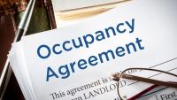 An Occupancy Agreement on top of a stack of pages on a desk